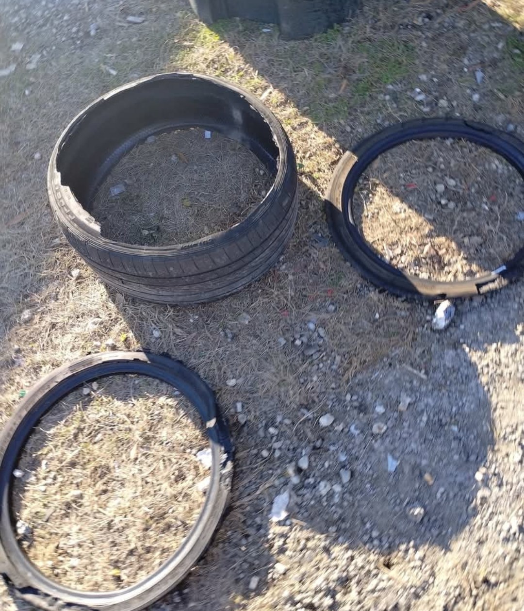 Three tires cut open after a blowout, laid out on gravel